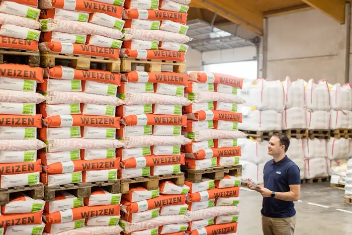 Mitarbeiter Michael Gradnitzer im Saatgut-Lager Korneuburg, vor gestapelten Säcken und Big-Bags mit Weizen-Saatgut, Totale